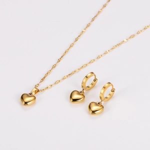 Detailed view of golden heart-shaped necklace and matching hoop earring jewelry set