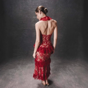 Back view of elegant red lace halter dress with ruffled hem in a studio setting