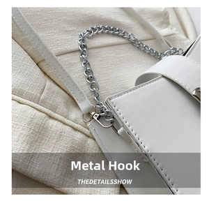 Close-up of silver metal chain strap and hardware hook on white faux leather bag