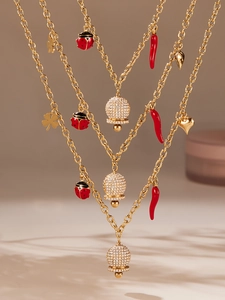 Détail du collier doré avec charms coccinelle rouge, piment et boules de cristal brillants