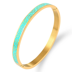 Close-up of gold stainless steel bangle featuring light blue enamel floral patterns