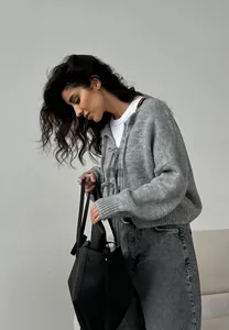 Détail d'un cardigan gris en maille avec texture douce et fermeture à nœud papillon