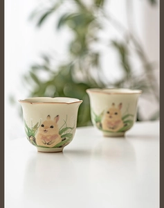 Detail of Ru kiln ceramic tea cups with hand-painted rabbit and petal-shaped rim