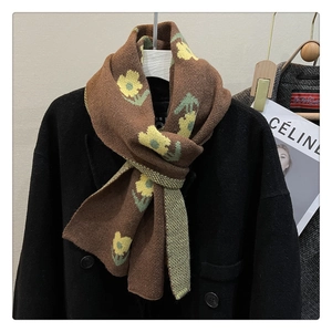 Detail of brown knitted scarf featuring yellow floral patterns on a wool-like texture