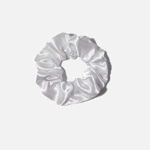 White satin silk scrunchie with elegant folds and elastic band on light grey background