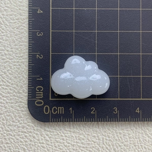 Macro shot showing white glitter cloud resin accessory dimensions on a black scale mat