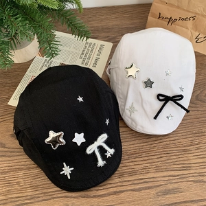 Japanese retro star and bow newsboy caps in black and white colors on a wooden table