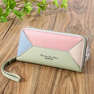 Women's long patchwork leather wallet with multi-card slots and wristlet strap on wood