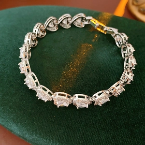 Detail of silver heart and oval zircon bracelet on green velvet background