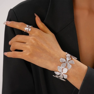 Close-up of silver textured floral open cuff and ring set on female model in black
