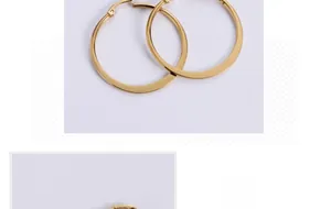 Detailed close-up of golden titanium steel hoop earrings featuring a pin-style clasp closure