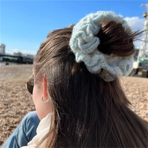 Detail of mint green crochet ruffle hair tie with soft knitted texture on wrist
