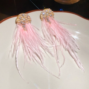 Detailed close-up of sparkling pink feather tassel earrings with rhinestone studs on a white plate