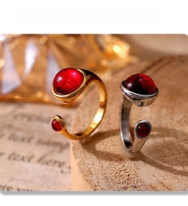 Detail of PVD gold and silver garnet rings with red stones on a wooden stand