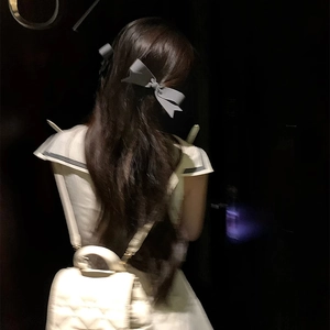 Elegant grey satin bow hair clip styled on model with white quilted backpack