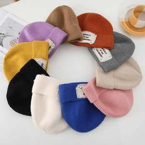 Flat lay of colorful knit beanies in purple, orange, and blue on a minimalist background
