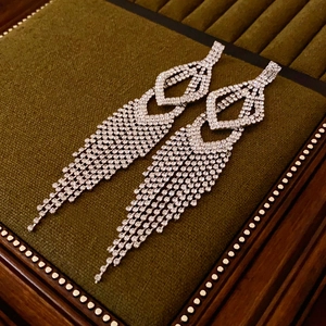 Macro detail of silver tassel earrings with sparkling rhinestones on green velvet