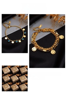 Close-up of gold layered chain bracelets with evil eye and smiley face pendants