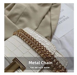 Detail of elegant crocodile-pattern leather bag with premium gold chain and metal clasp