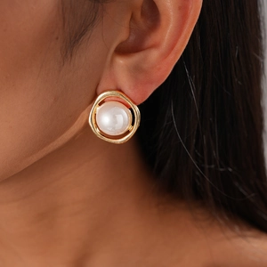 Detailed close-up of a vintage irregular gold metal earring with a white faux pearl