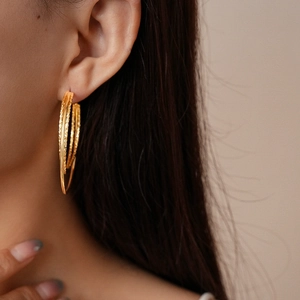 Detailed close-up of 18k gold-plated triple-layer hoop earrings with diamond-cut texture
