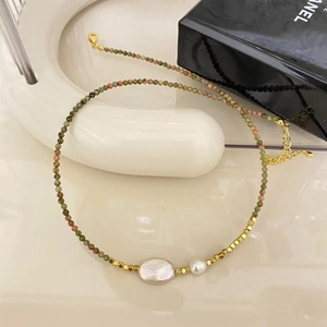 Macro shot of colorful tourmaline beads and a baroque freshwater pearl on a golden chain