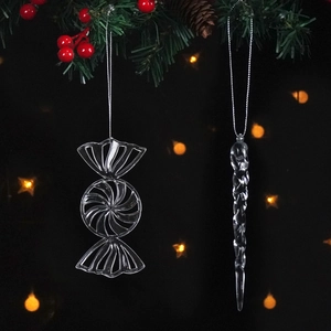 Clear acrylic Christmas lollipop and icicle ornaments hanging on a festive pine tree branch