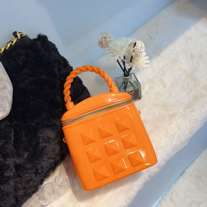 Detail of orange jelly bucket bag featuring square studs and a woven handle design
