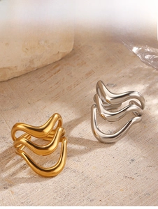 Close-up of wavy gold and silver stacked rings on a natural stone background with reflections