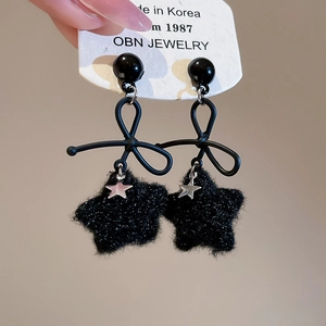 Close-up of black velvet star earrings with bow detail and silver star pendant