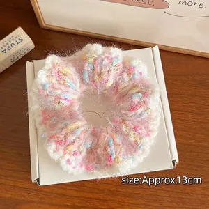 Chouchou en tricot coloré rose et bleu de 13 cm posé sur une boîte blanche et table en bois