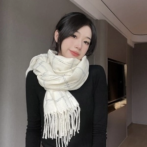 Detail shot of soft white checkered tassel scarf on a model showing plush texture and warmth