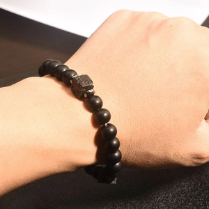 Dettaglio del bracciale di ossidiana nera con ciondolo a corona sul polso