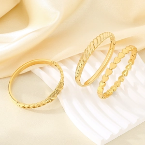 Detailed close-up of three gold-plated textured bangles with heart and twist patterns