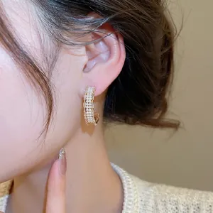 Gold plated C-shaped earrings with pearls and rectangular zirconias on model