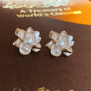 Macro shot of pearl flower stud earrings with white enamel petals and gold edges