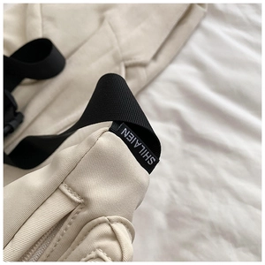 Close-up of minimalist cream crossbody bag showing premium stitching and logo strap