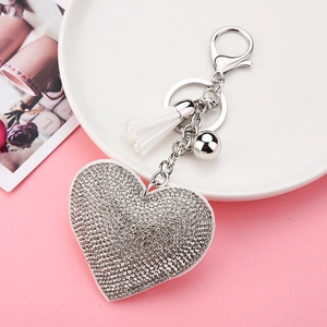 Sparkling silver heart keychain with white fringe tassel and rhinestones on pink display