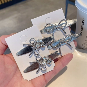 Elegant silver metal bow hair clips with pearls and rhinestones on white card