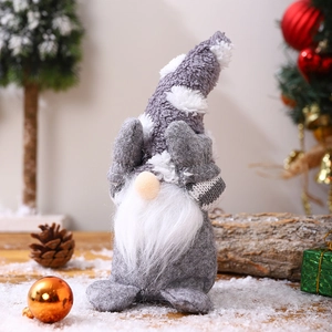 Detailed view of a grey plush Christmas gnome with white beard sitting in festive decor