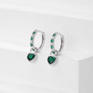 Detail of silver heart earrings featuring alternating green and white cubic zirconia