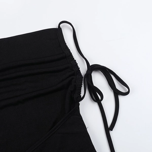 Close-up detail of the adjustable drawstring side ties and ruched fabric on the black jumpsuit