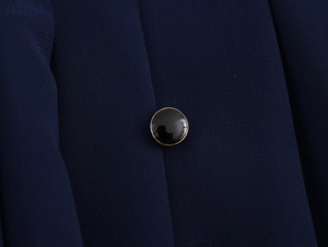 Detailed macro shot of a black button with gold trim on dark blue textured fabric