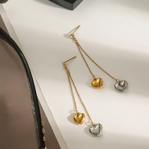 Elegant gold and silver heart tassel earrings with rhinestones on a magazine background