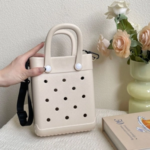 Detail of beige EVA tote bag featuring circular cutouts and black adjustable strap