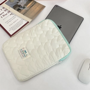 Detalle de funda blanca acolchada con diseño de corazones y cremallera verde menta