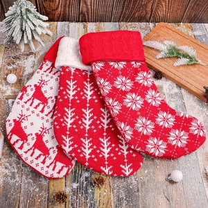 Three knitted Christmas stockings with reindeer and snowflake patterns on wood background