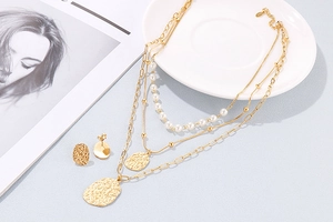 Close-up of layered gold necklace set with S925 hallmark and pearl chain details