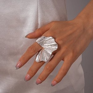 Detailed close-up of a silver oversized irregular textured ring on a silk background