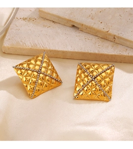 Close-up of golden square stud earrings with diamond texture and silver bead cross detail